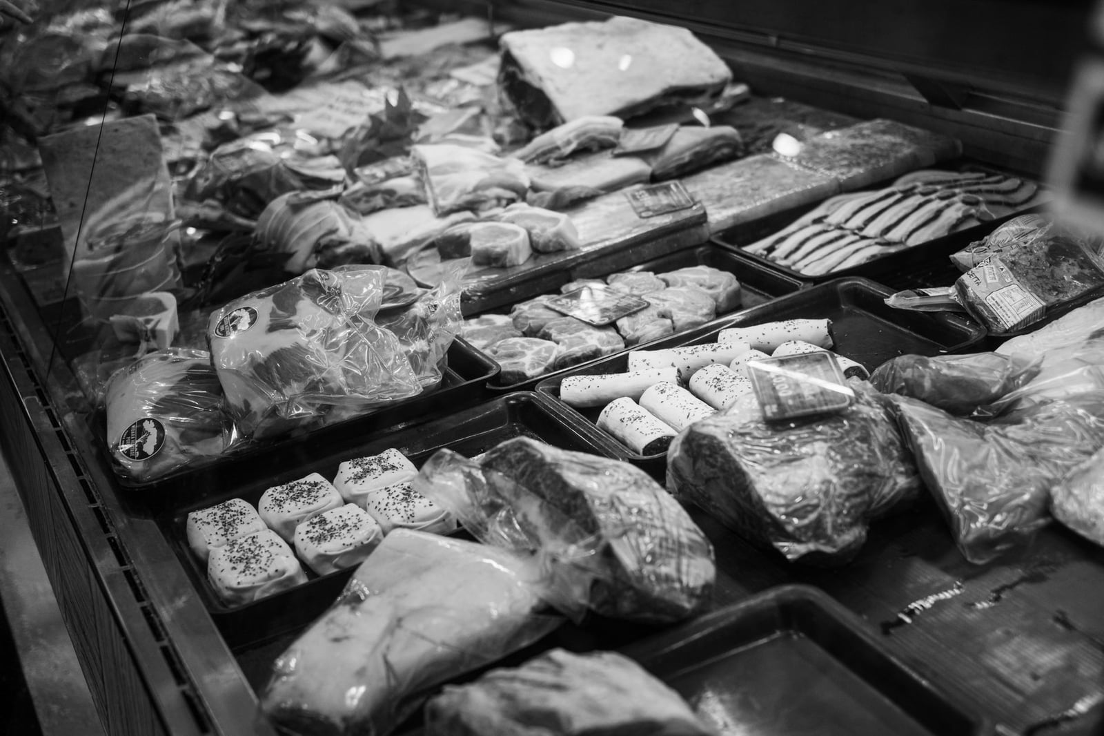 Una exhibición de carnicería en monocromo con diversos productos cárnicos envasados.