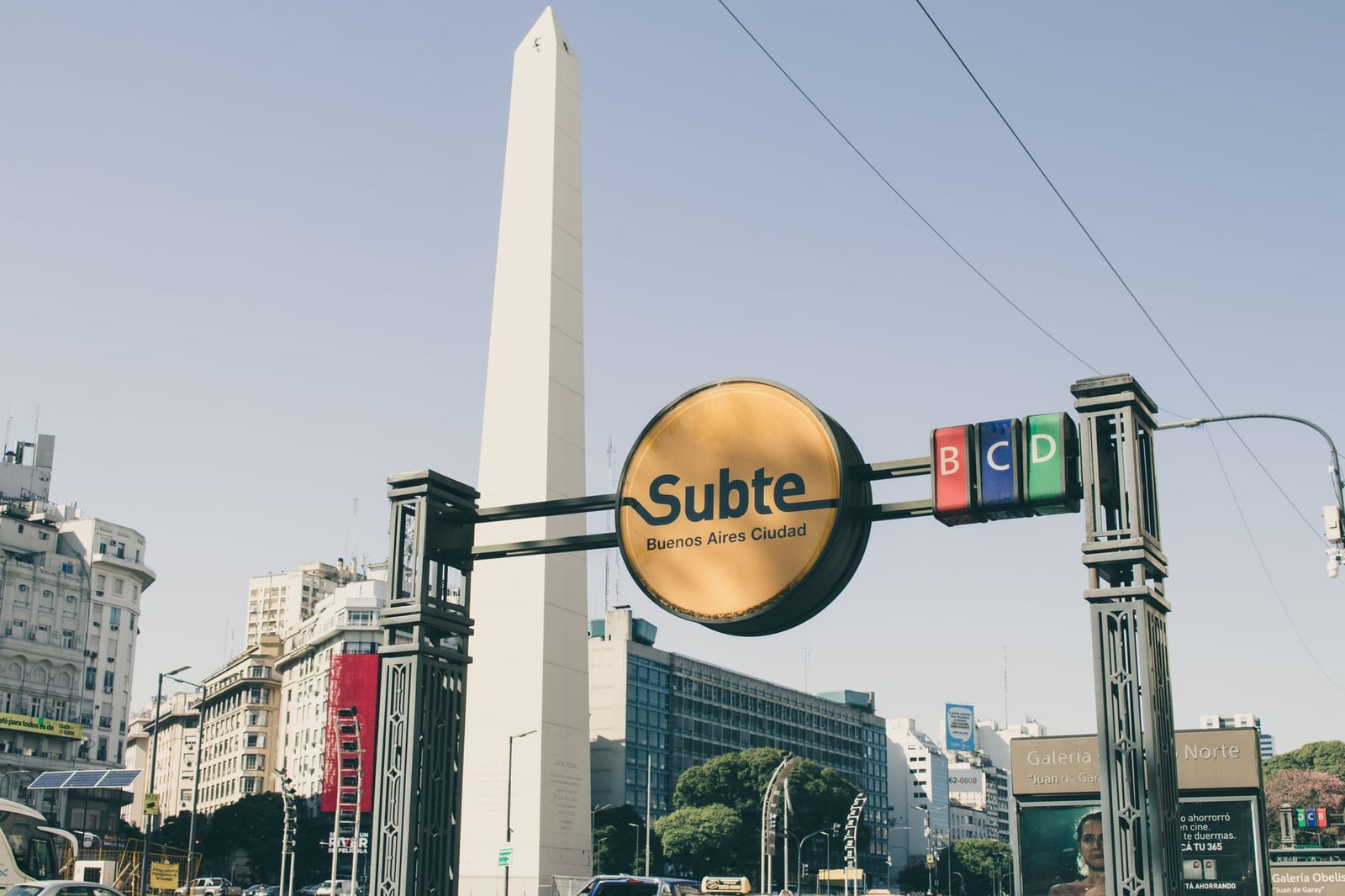Vista del Obelisco en Buenos Aires con señalización del Subte prominente contra un cielo despejado.