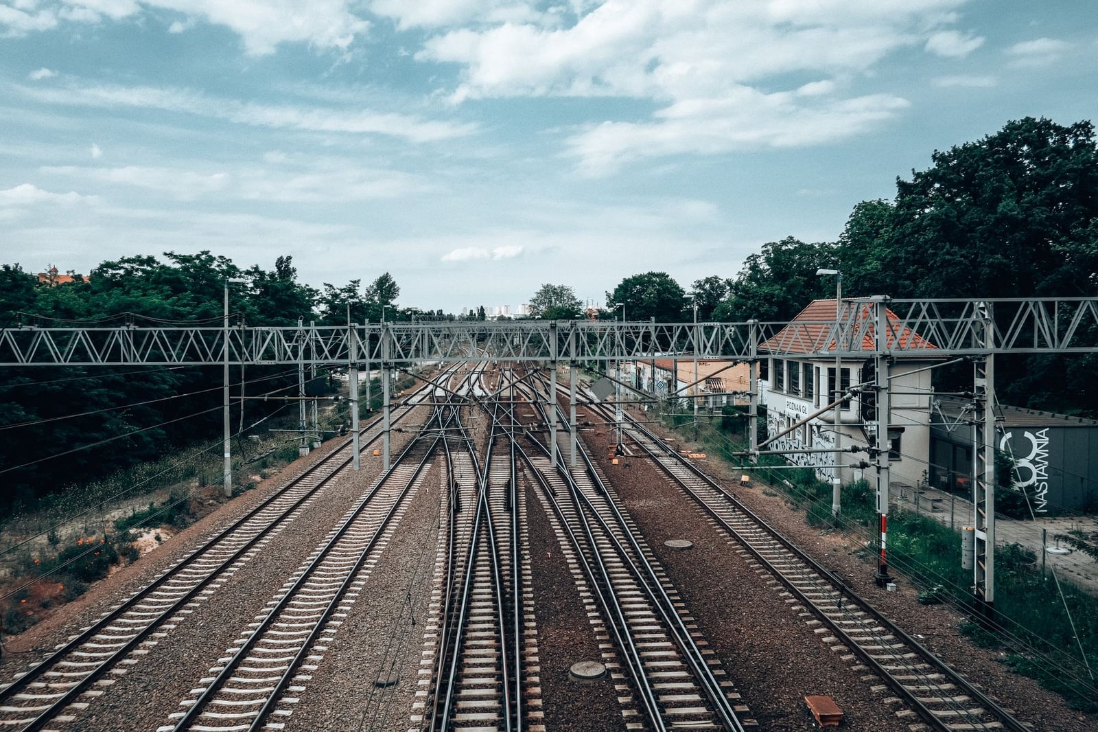 Una vista escénica de las vías del tren bajo un cielo despejado en Poznań, mostrando estructuras de acero y un entorno urbano.