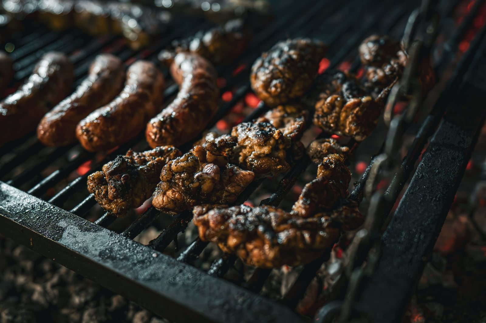 Carnes jugosas asándose sobre carbón, mostrando un estilo tradicional de asado.