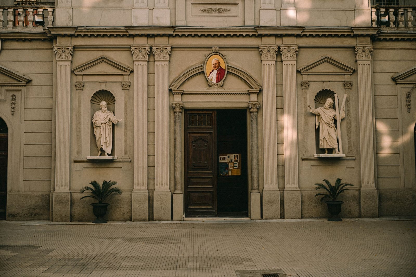 Elegante fachada de iglesia con estatuas y retratos religiosos bajo una cálida iluminación.