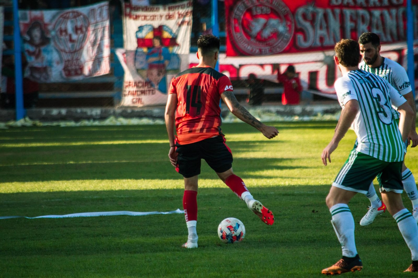 Partido de fútbol dinámico con jugadores en acción en un estadio en Mendoza, Argentina.
