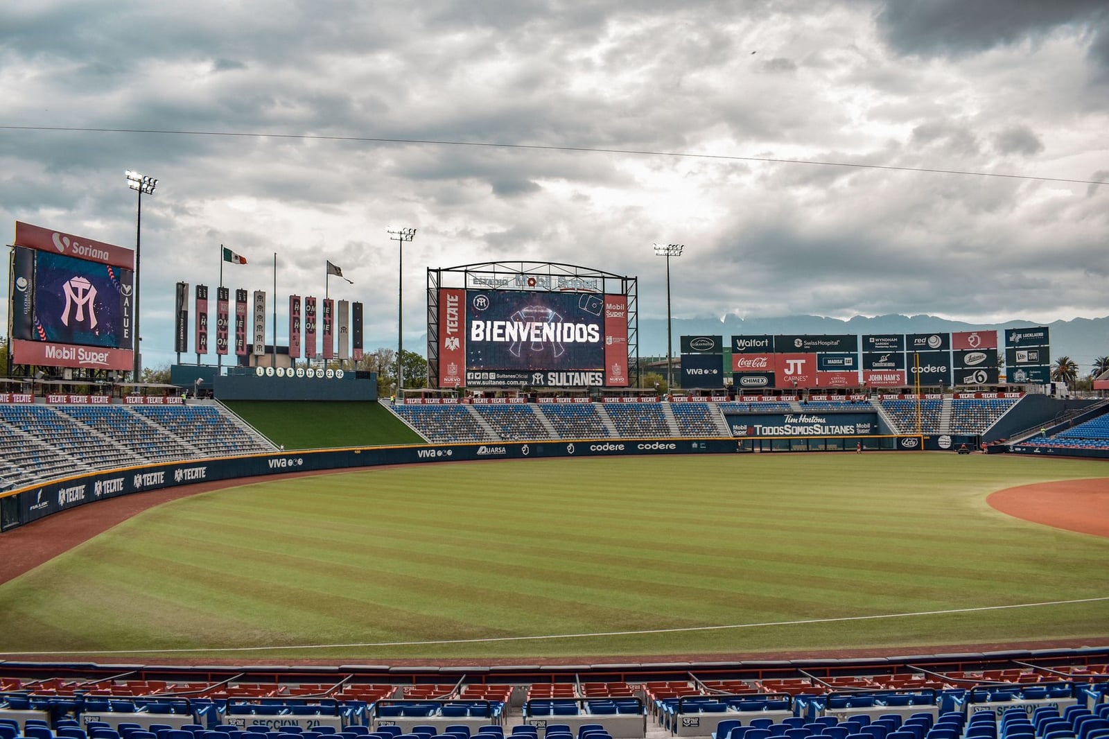 Estadio de béisbol vacío en Monterrey, México, con cartel electrónico de bienvenida.