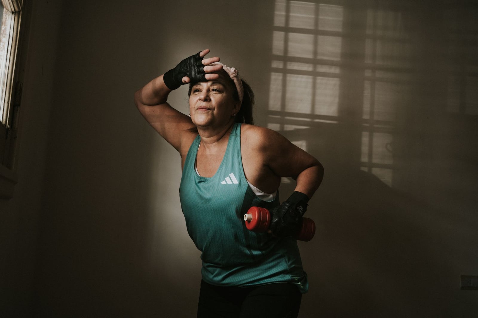 Mujer de mediana edad haciendo ejercicio con una mancuerna en interiores. Concepto de fitness y estilo de vida saludable.