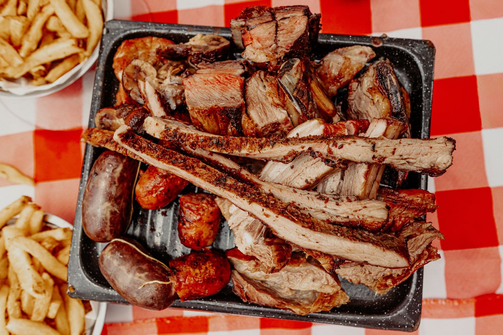 Un apetitoso plato de asado argentino con carnes a la parrilla sobre un mantel tradicional a cuadros.