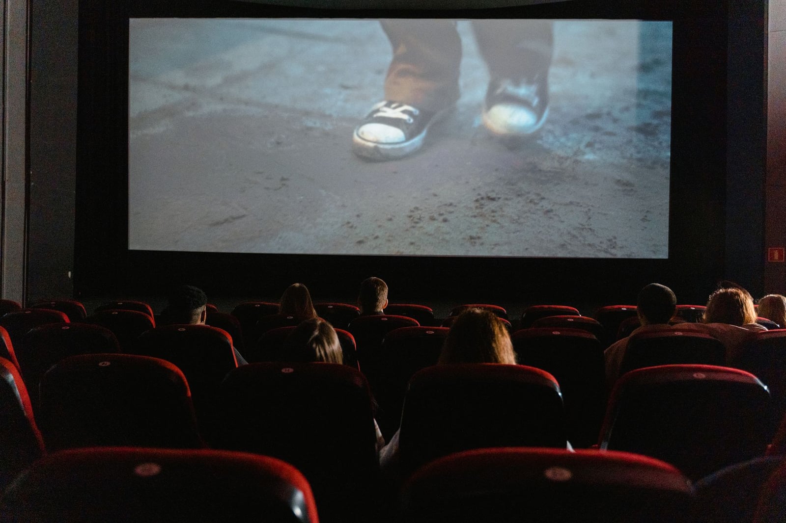 Un grupo de personas disfrutando de una película en un cine con una pantalla grande.
