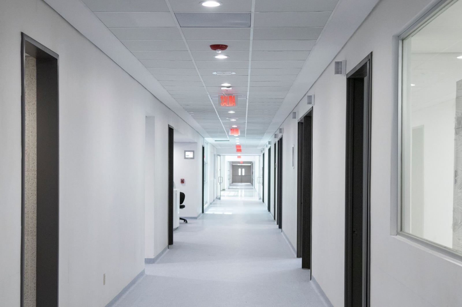 Pasillo de hospital con paredes blancas, diseño moderno y una brillante iluminación overhead.