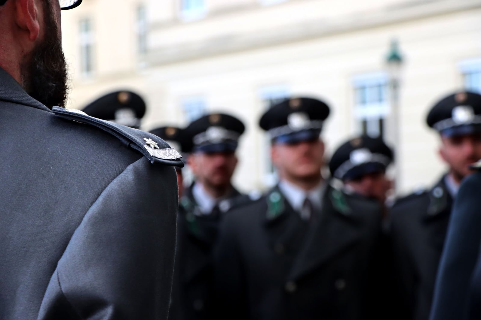 Grupo borroso de oficiales uniformados en formación, centrándose en la insignia y los detalles del uniforme.