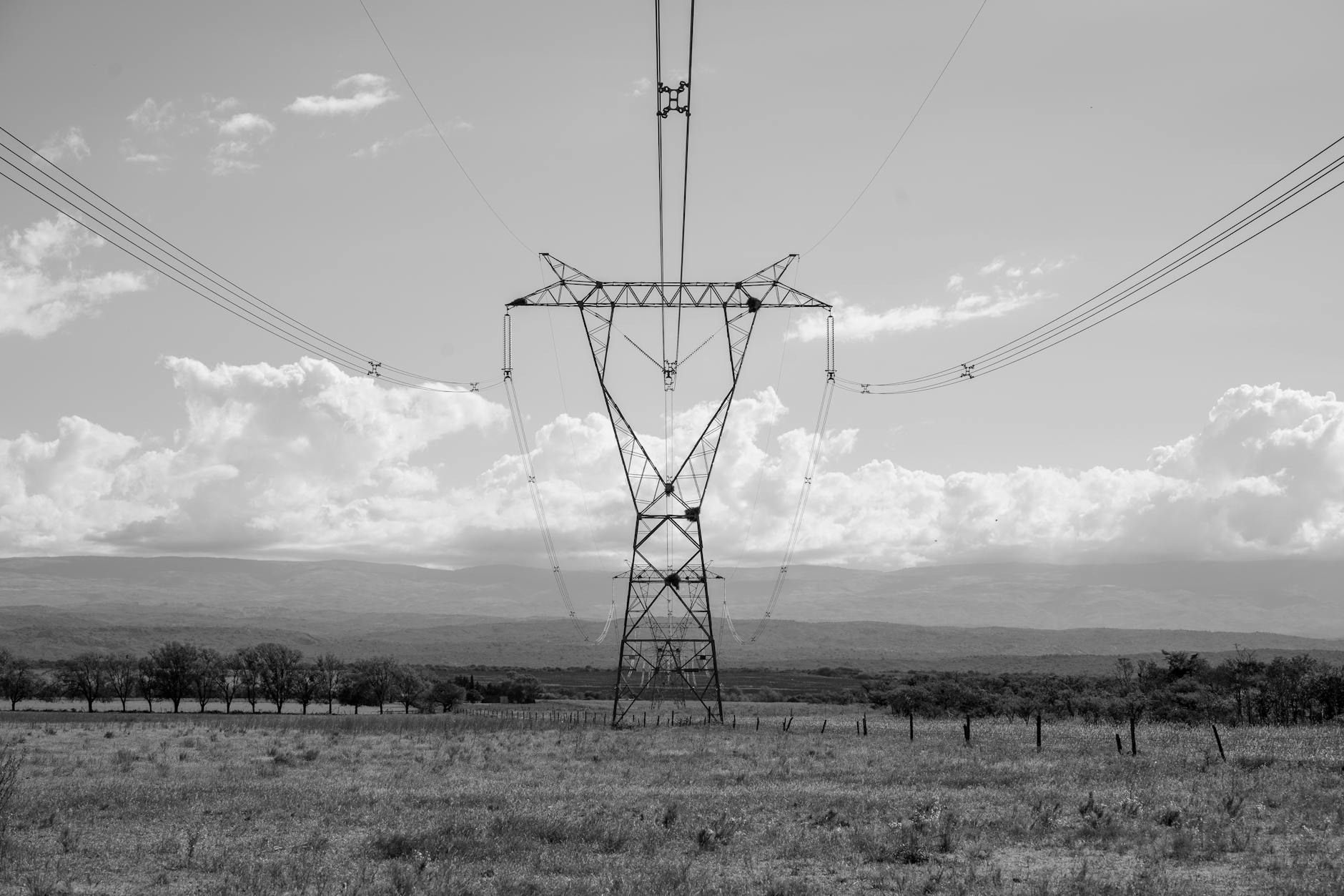Imagen en blanco y negro de una torre de transmisión eléctrica en un vasto paisaje de Córdoba, Argentina.