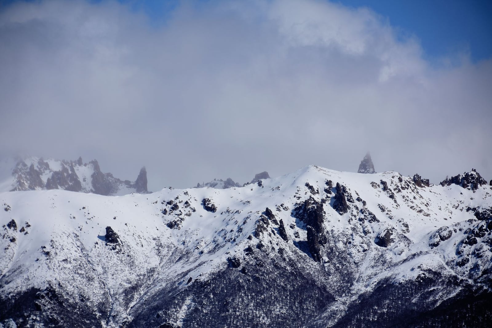 Impresionantes cumbres nevadas de los Andes en Bariloche, Argentina, bajo un cielo nublado.