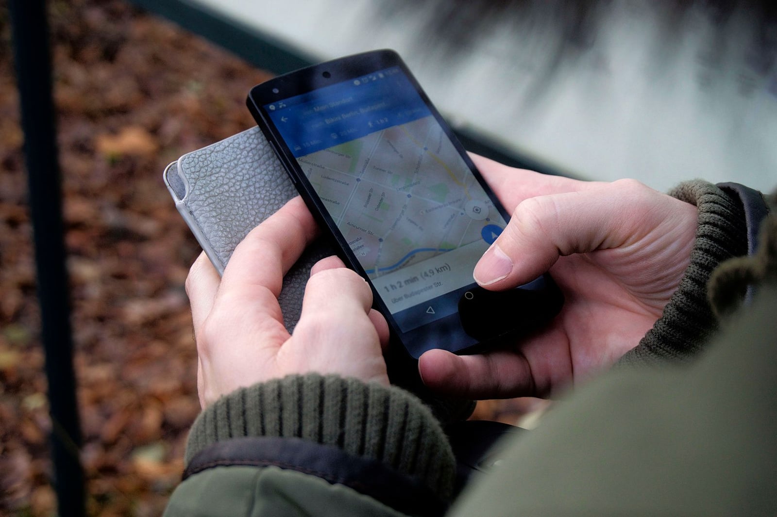 Primer plano de manos utilizando una aplicación de mapas en un smartphone al aire libre, mostrando navegación GPS.