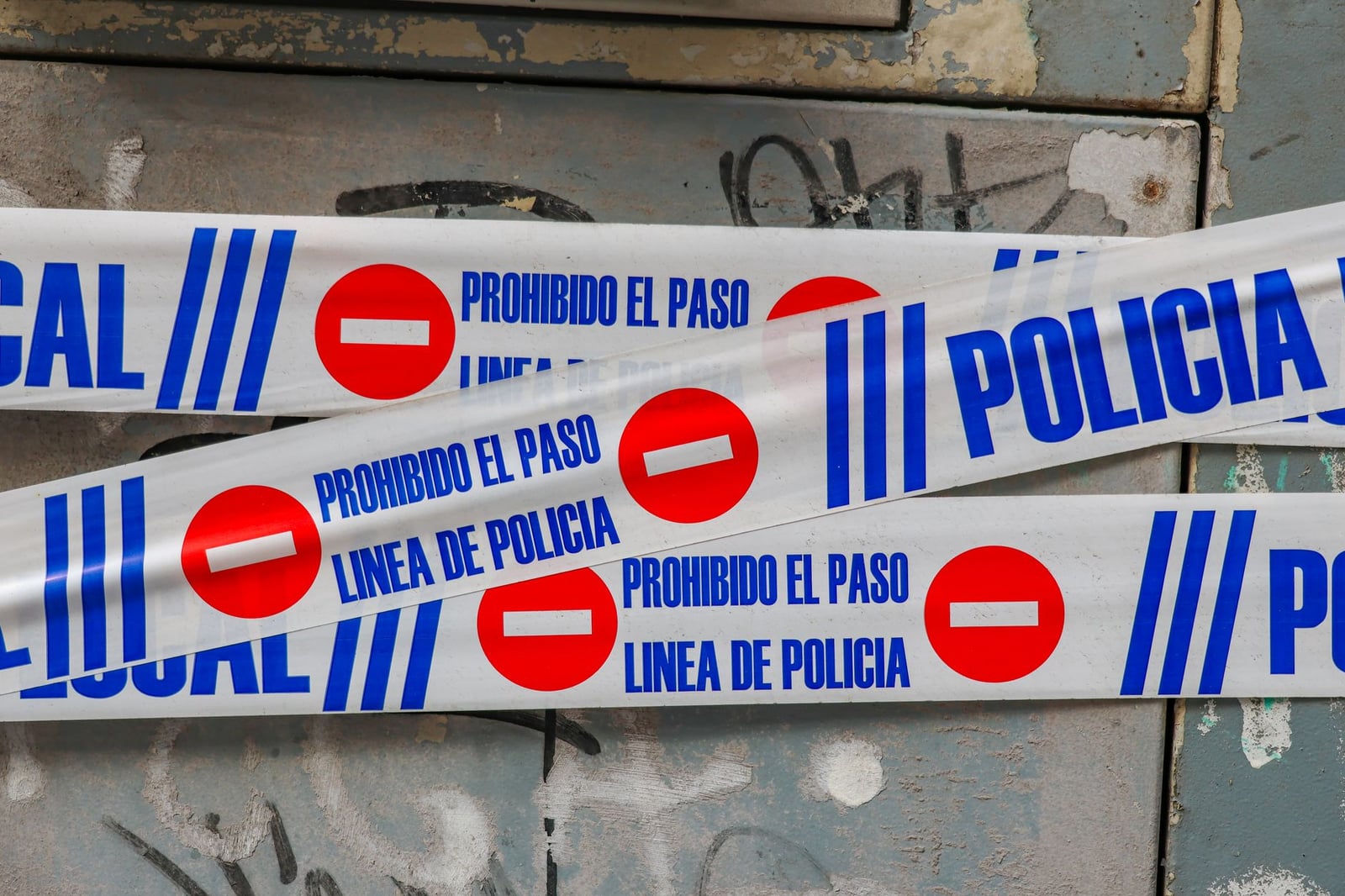 Cinta policial con la leyenda "Prohibido El Paso" contra un muro cubierto de grafitis. Concepto de escena del crimen.