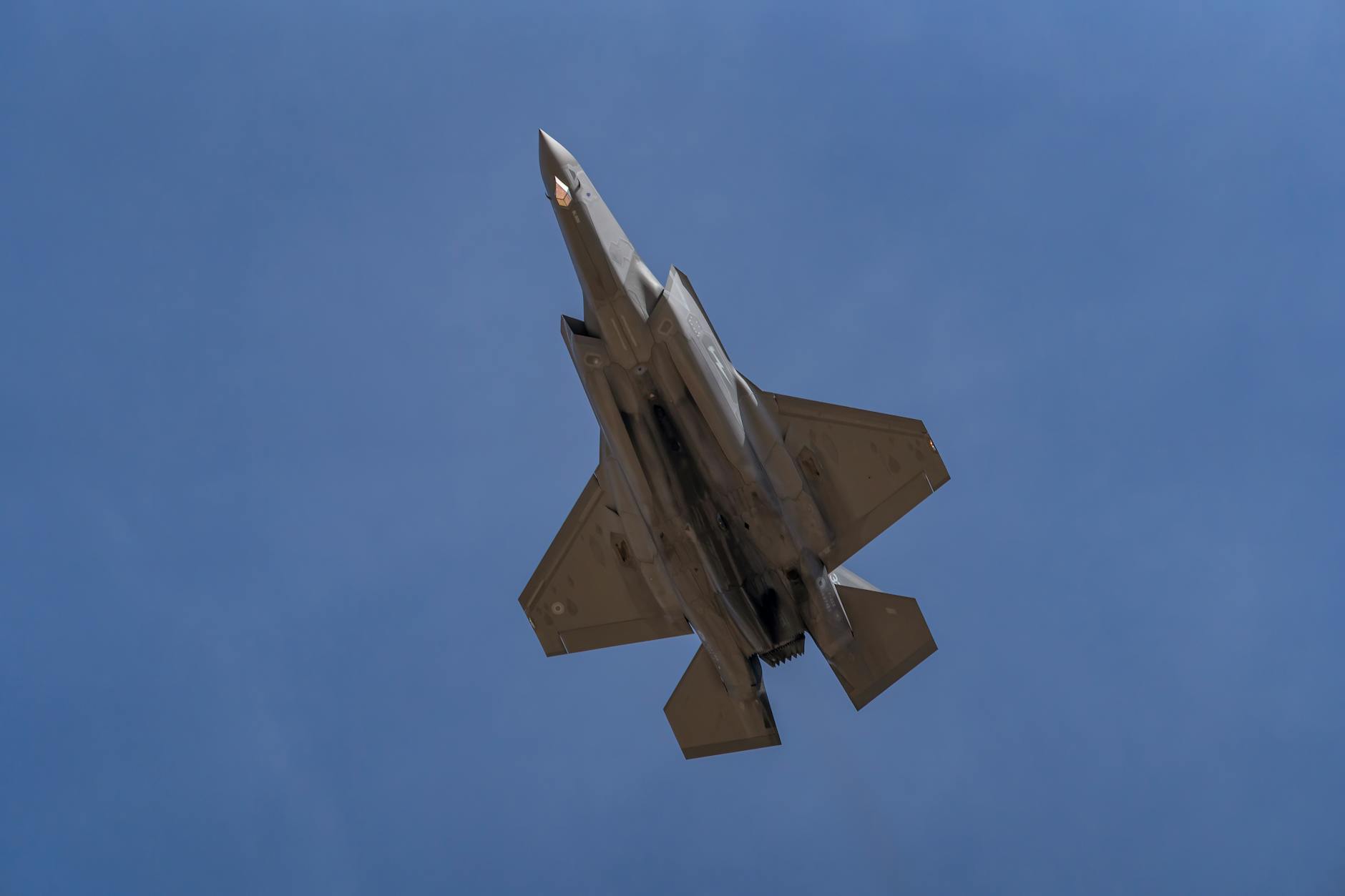 Una captura dinámica de un avión F-35 volando contra un cielo azul claro en Los Llanos, España.