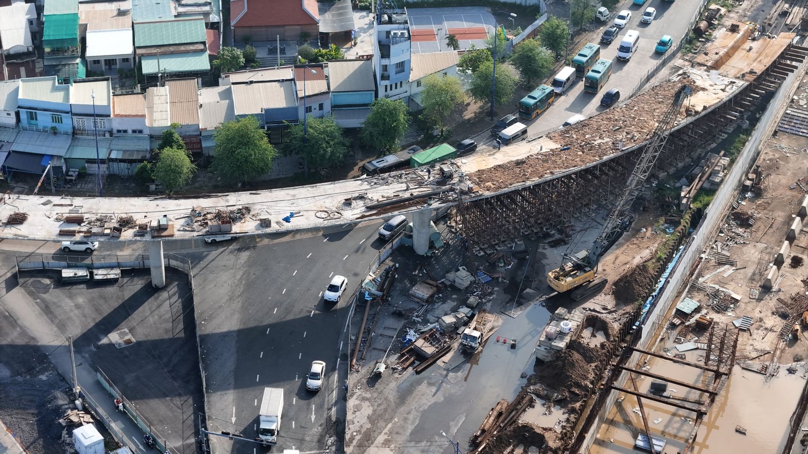 Una toma aérea de una carretera en construcción con vehículos y maquinaria, que muestra el desarrollo urbano.