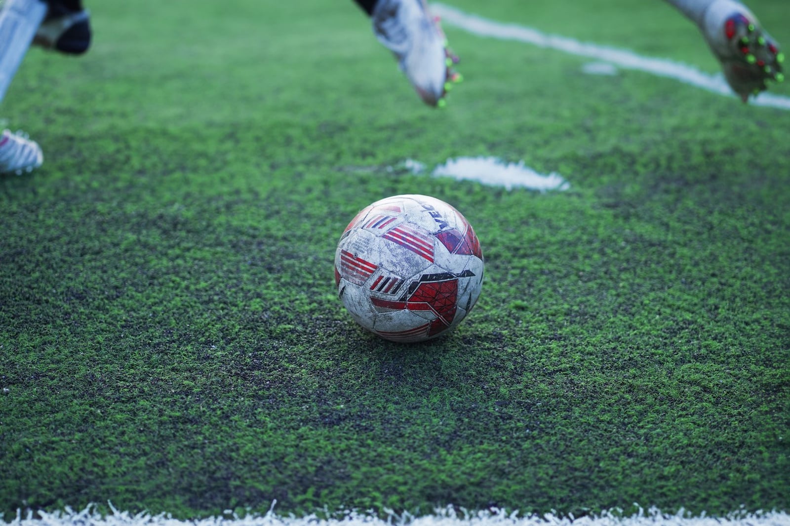 Primer plano detallado de un balón de fútbol en un campo de hierba verde mojada durante el juego.