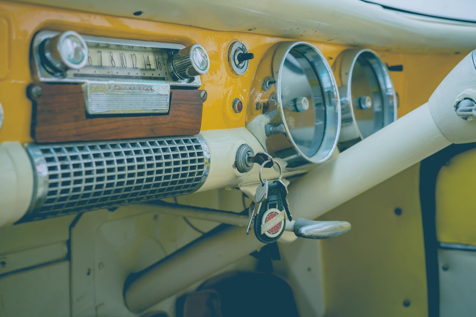 Acercamiento al salpicadero de un coche vintage clásico con radio analógica, velocímetro y llaves.