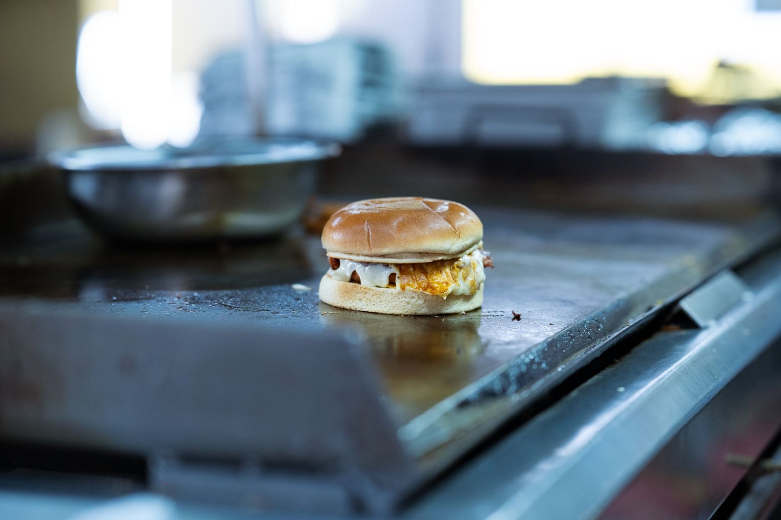 Primer plano de una hamburguesa con queso fundido en la plancha de la cocina de un restaurante. Fotografía gastronómica perfecta.