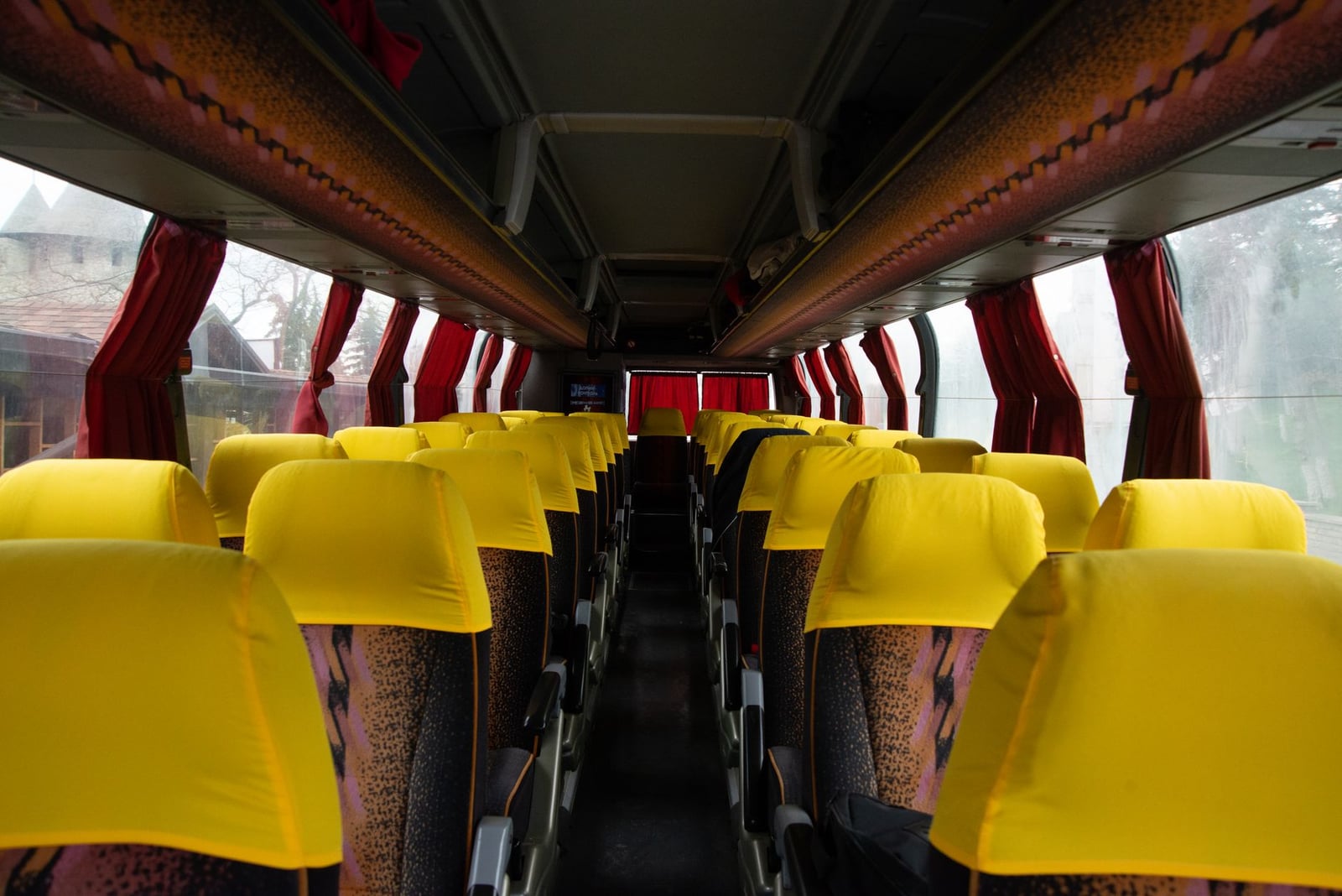 Interior espacioso de autobús con asientos amarillos brillantes y cortinas rojas, ideal para imágenes de viaje y transporte.