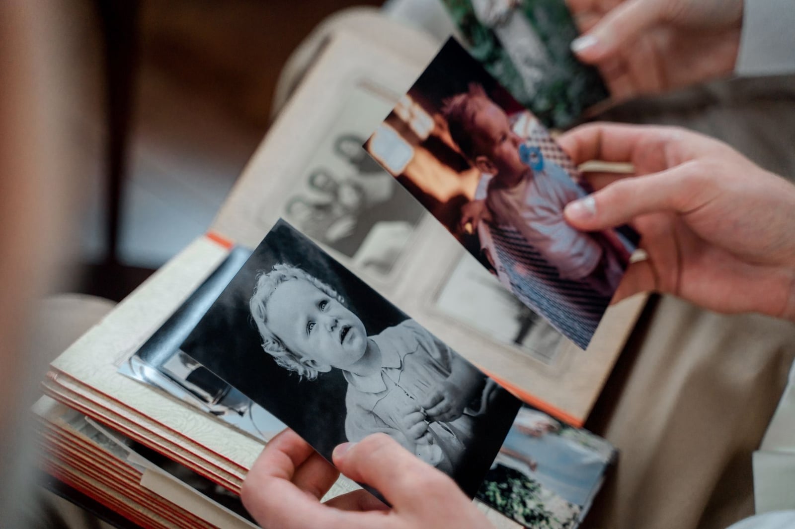 Primer plano de manos examinando fotos familiares nostálgicas en un álbum.