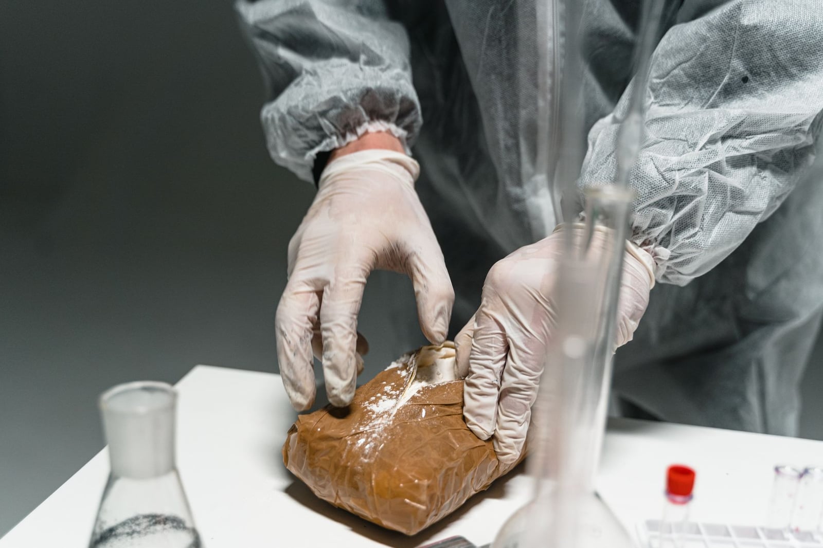 Trabajador de laboratorio analiza sustancia en polvo en un entorno de laboratorio utilizando equipo de seguridad.